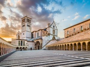 Famous Basilica of St. Francis of Assisi (Basilica Papale di San Francesco) with Lower Plaza at sunset in Assisi, Umbria, Italy